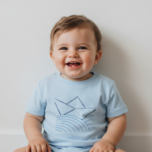Baby blue cotton T-shirt with boat and wave graphic, child smiling in front view