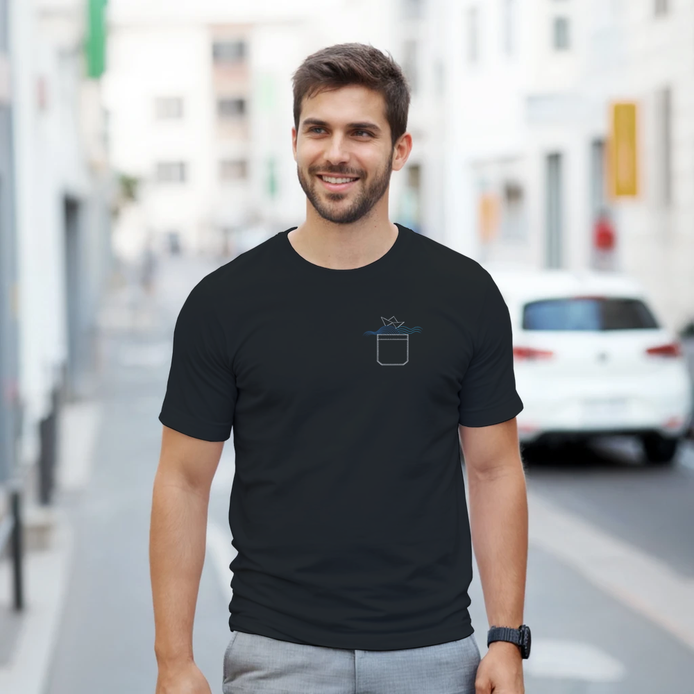 Man wearing a black t-shirt with an origami boat design, on a city street.